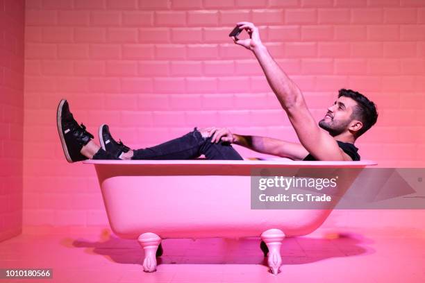 man taking a selfie in the pink bathtube - influencer man stock pictures, royalty-free photos & images