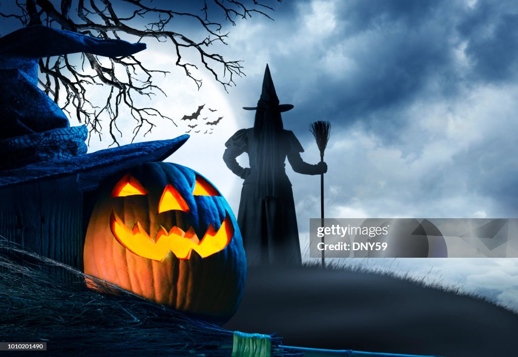 Witch Stands On Small Hill In Front Of Halloween Moon