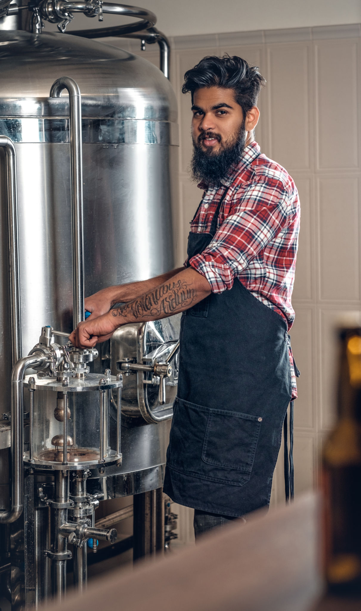 Indianr male manufacturer presenting craft beer in the microbrewery. Indianr male manufacturer presenting craft beer in the microbrewery.