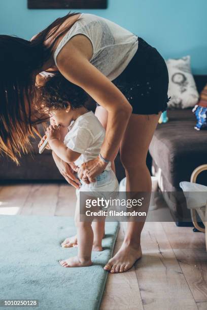 madre che cambia pannolino sul bambino mentre è in piedi - adult baby boy diaper change foto e immagini stock