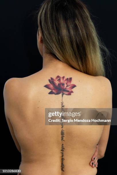 a young woman's back with a lotus flower tattoo - lotus flower tattoo stock-fotos und bilder