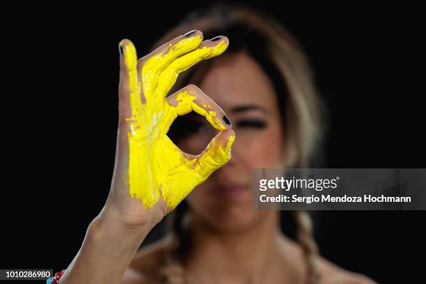 a young woman with yellow painted hand gives ok sign - zero stock pictures, royalty-free photos & images