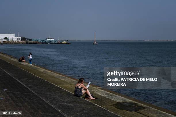 Woman reads a book at Ribeira das Naus in Lisbon on August 3, 2018. - Two men died from heatstroke in Spain as Europe sweltered in a record heatwave...