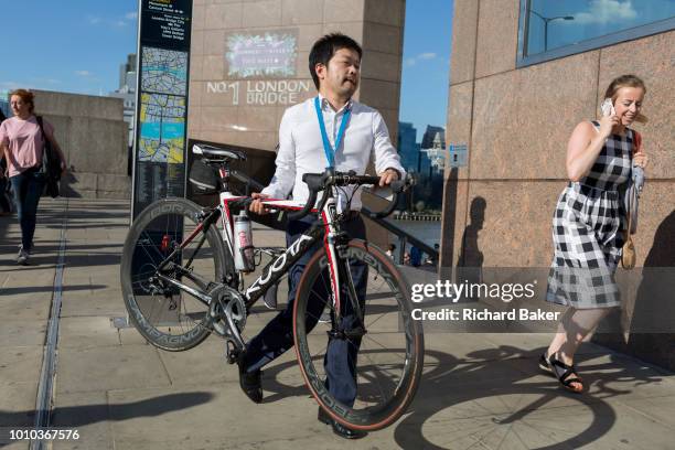 Man carries a bike while commuters walk southwards over London Bridge, from the City of London - the capital's financial district founded by the...