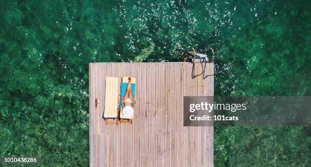 beautiful woman sunbathing alone on a wooden pier in sea aerial photo - beach bag overhead stock pictures, royalty-free photos & images