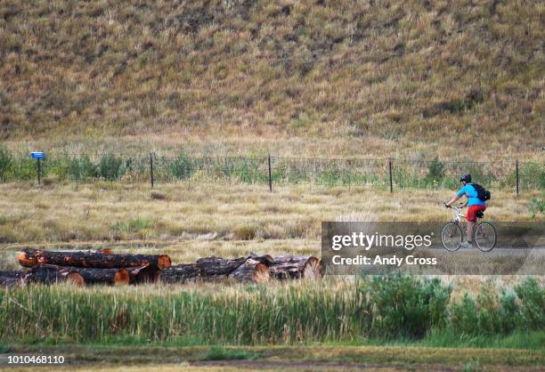 Cyclist makes their way down the Cherry Creek bike path just below the Cherry Creek Dam August 03, 2018.