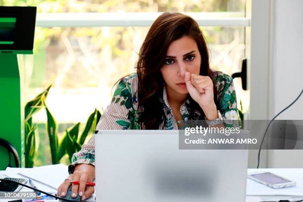 Clinical psychologist Mia Atwi, co-founder of Embrace, a suicide prevention helpline, reads emails in the Lebanese capital Beirut on July 13, 2018. -...