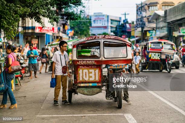 negros oriental dumaguete area by day tricycles with passengers and pedestrians on the street - negros_(philippines) stock pictures, royalty-free photos & images