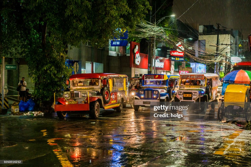 Manila Malate area by night city street jeepneys pedicabs on the street on a rainy night