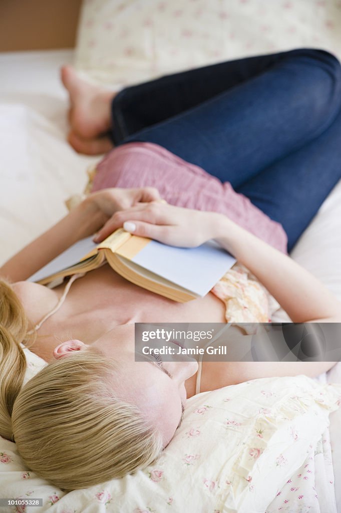 Woman relaxing on bed with book 