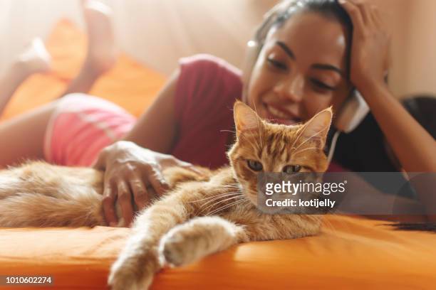 mujer feliz en casa escuchando música y abrazar su gato - fond orange fotografías e imágenes de stock