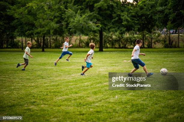 jungs spielen fußball im park - club soccer stock-fotos und bilder