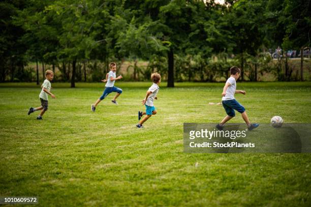 jongens voetballen in het park - club soccer stockfoto's en -beelden