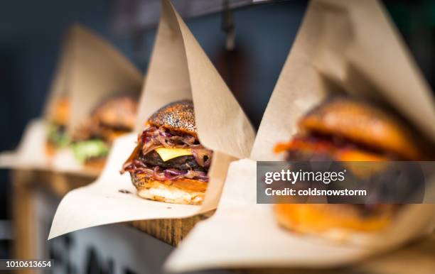 frische flamme gegrillte burger in einer reihe am lebensmittelmarkt angezeigt - american burger stock-fotos und bilder