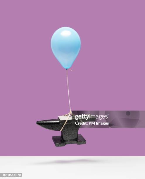 balloon lifting an anvil - simple concept stock pictures, royalty-free photos & images