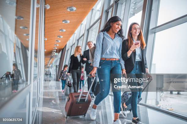 amiche che camminano vicino alla finestra all'aeroporto - airport passenger foto e immagini stock