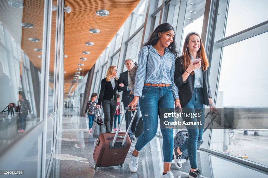 Female friends walking by window at airport
