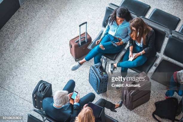 passengers sitting on seats in departure area - airport stock pictures, royalty-free photos & images