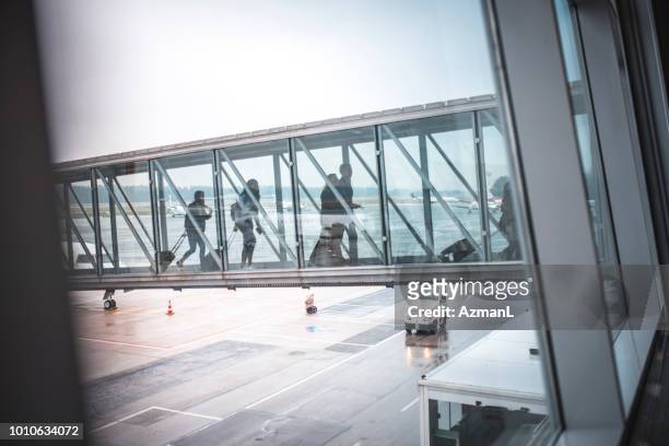 passengers on footbridge at airport terminal - airport wall stock pictures, royalty-free photos & images