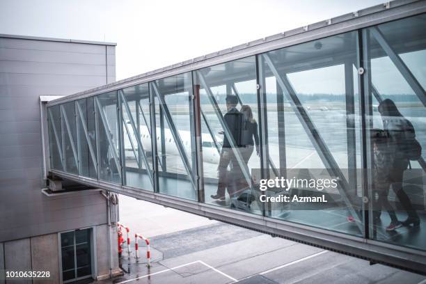 passengers walking on footbridge at airport - bridge building glass stock pictures, royalty-free photos & images