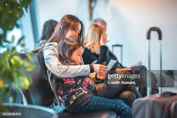 family with tickets waiting at airport terminal - airport sitting family stock pictures, royalty-free photos & images