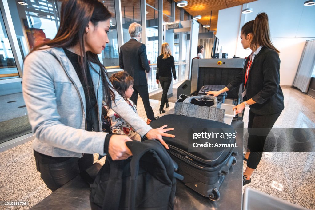 Family with luggage at airport security check