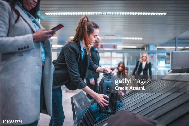 colegas con equipaje en cinta transportadora - zona de equipajes fotografías e imágenes de stock