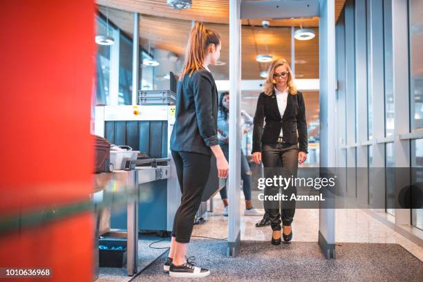 female passing through metal detector at airport - posto de controlo de segurança imagens e fotografias de stock