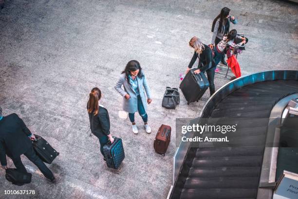 people with luggage by conveyor belt at airport - baggage claim stock pictures, royalty-free photos & images