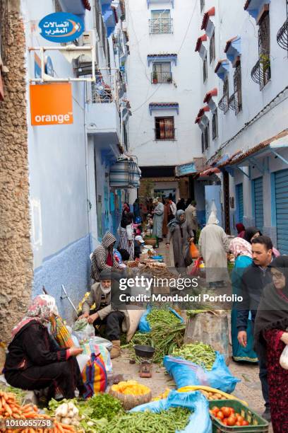 Women and men sell the products of their earth, fruit and vegetables, to the market in a street of Chefchaouen, April 2018