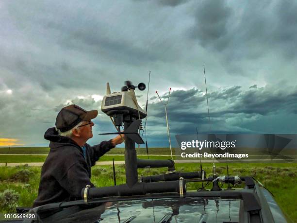 storm chaser ajusta la estación en la azotea en su vehículo de persecución como una tormenta severa se basa en el fondo - weather station fotografías e imágenes de stock