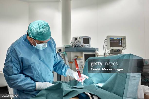 surgeon monitoring bone marrow extraction procedure - bone marrow transplant foto e immagini stock