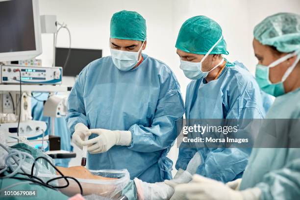 team of surgeons injecting patients with stem cells - ropa de operar fotografías e imágenes de stock