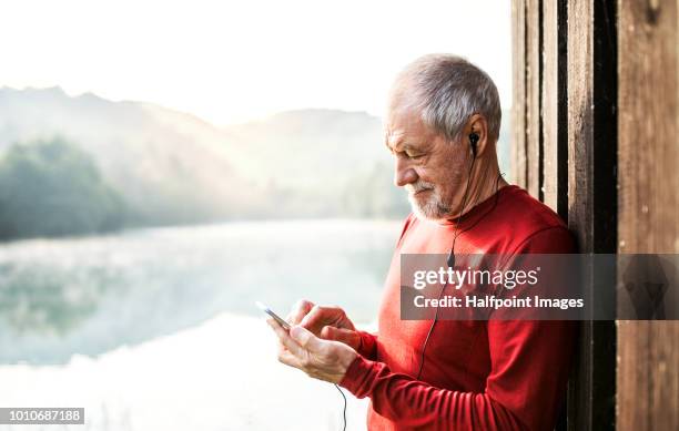 a portrait of an active senior man with smartphone and earphones outdoors in nature in the foggy morning. copy space. - runner sunrise stock pictures, royalty-free photos & images