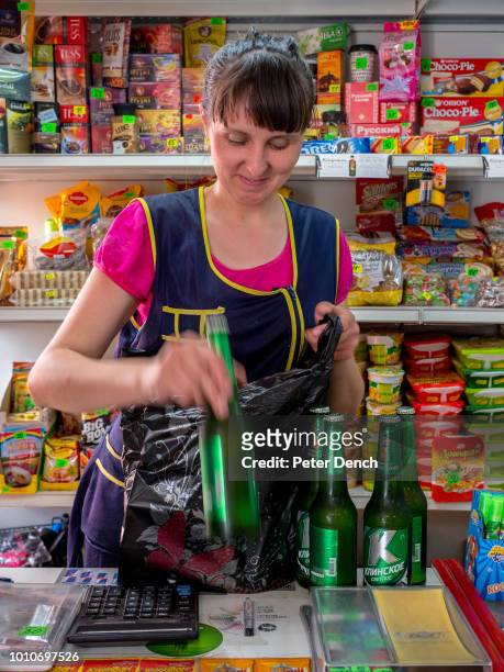 Beer is packed in a bag by a shop keeper near Omsk station. The 50 minute stop allows passengers to buy supplies for their journey on the...