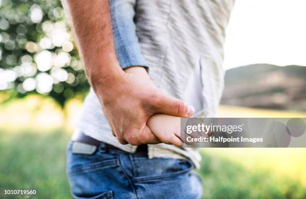 a father giving a small girl a piggyback ride outside in spring nature. - girls barefoot in jeans fotografías e imágenes de stock