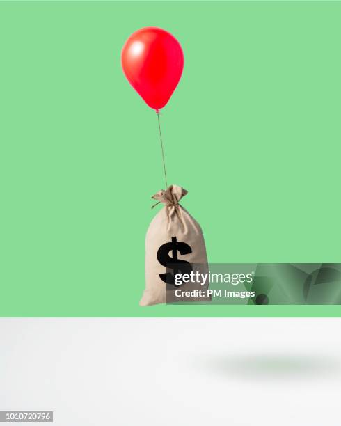 balloon carrying money bag, studio shot - money bag fotografías e imágenes de stock