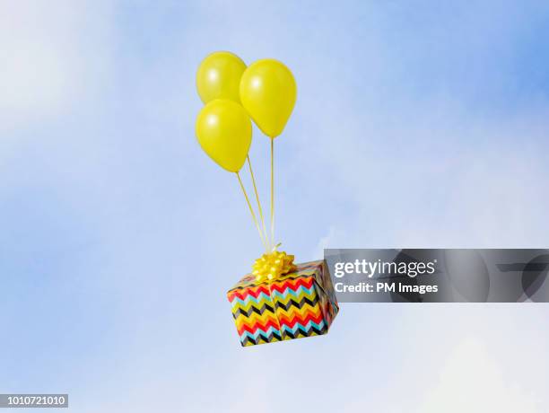 helium balloons carrying gift - anreiz stock-fotos und bilder