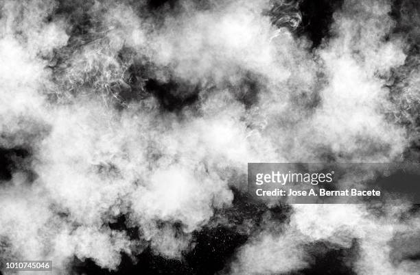 full frame of forms and textures of an explosion of powder and smoke of color white on a black background. - nebel stock-fotos und bilder