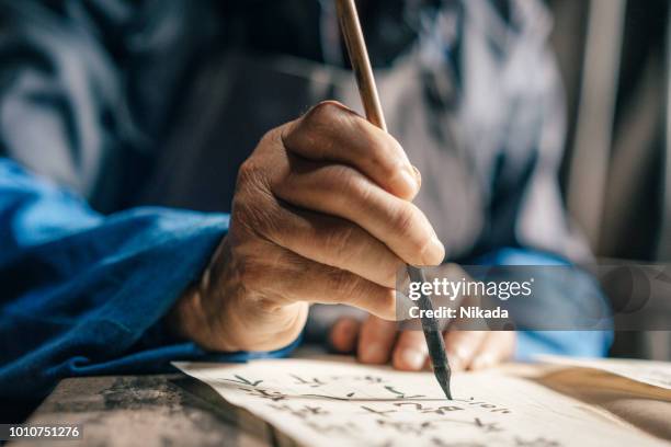 old hands of man writing chinese script - - chinese symbols stock pictures, royalty-free photos & images