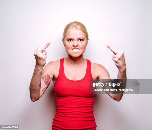 angry young woman in red shirt - doigt dhonneur stockfoto's en -beelden