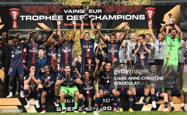 Paris Saint-Germain's Brazilian defender Thiago Silva holds the trophy as he celebrates with teammates after winning the French Trophy of Champions...