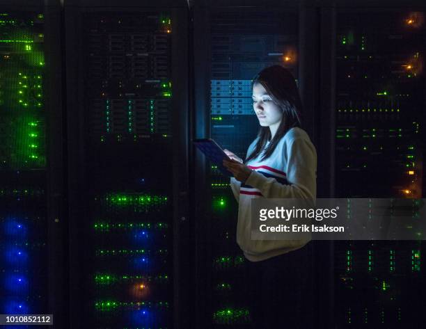 young woman working on digital tablet in server room - server room women foto e immagini stock