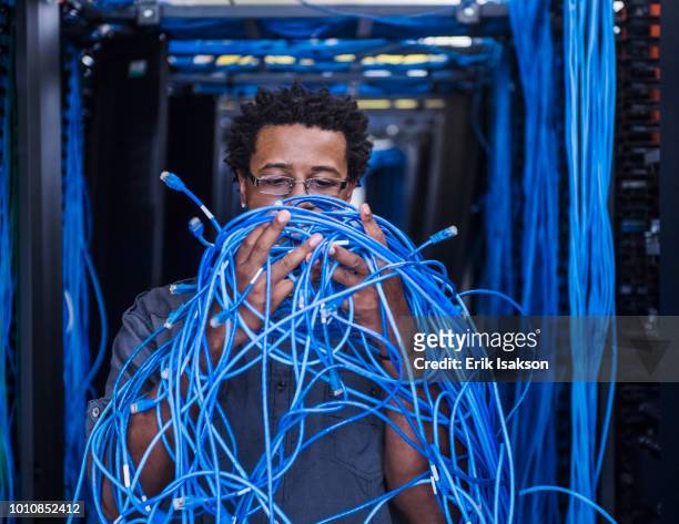 man with tangled cables in server room - tangle stock pictures, royalty-free photos & images