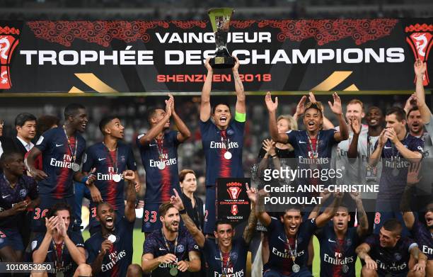 Paris Saint-Germain's Brazilian defender Thiago Silva holds the trophy as he celebrates with teammates after winning the French Trophy of Champions...
