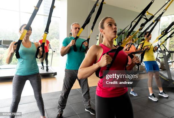 instructor teaching a suspension training class at the gym - suspension training stock pictures, royalty-free photos & images