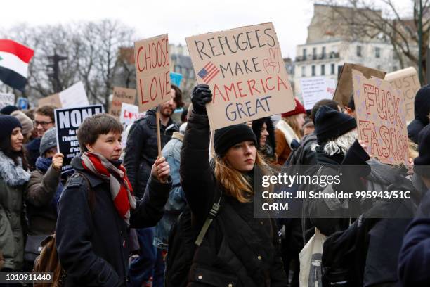 people hold signs at an anti-trump protest in paris. - anti trump protestors march in paris stock pictures, royalty-free photos & images