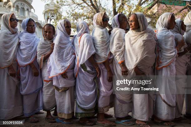 Widows line up to receive donated saris the day before a Holi celebration instead of the typical white saris widows are expected to wear.