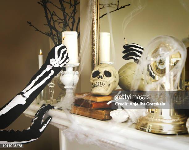 person dressed in a skeleton costume lights a candles. halloween composition on fireplace - halloween decoration fotografías e imágenes de stock