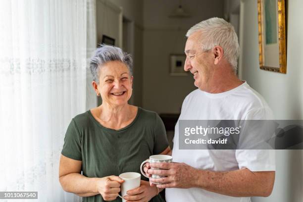 heureux couple de personnes âgées bénéficiant d’une tasse de thé à la maison - old people australia photos et images de collection